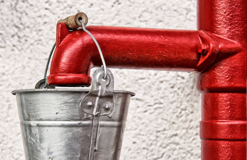 Eimer und Wasserpumpbrunnen